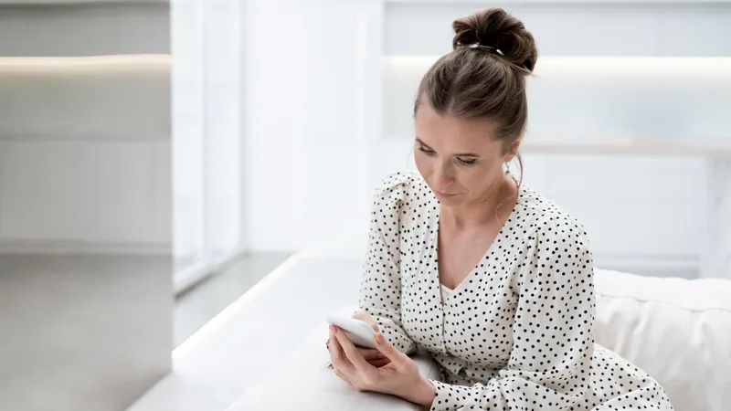 A clinician sitting by a window, reading on a phone